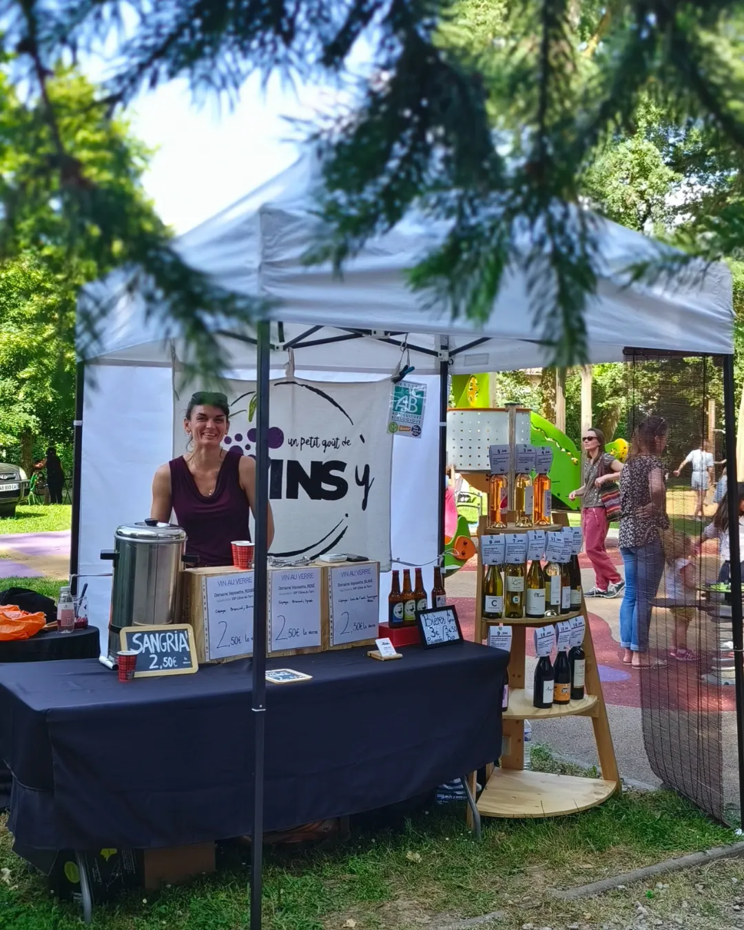 Stand Revinsy en extérieur avec Tania et une sélection de bouteilles.